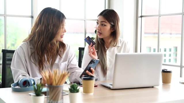 Two Asian female roommates holding credit cards, shopping online, holding credit card in bedroom at apartment