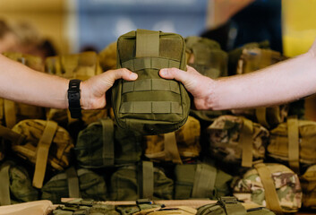 Military tactical first aid kit in camouflage. They hold hands, hand over a military first aid kit. volunteers help the army