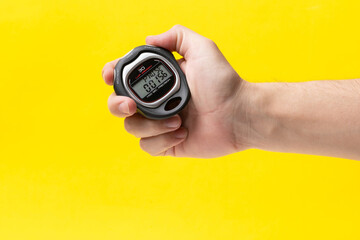Man hand holding stopwatch on yellow background, closeup. Time management concept. - Powered by Adobe