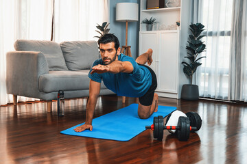 Flexible and dexterity man in sportswear doing yoga position in meditation posture on exercising...