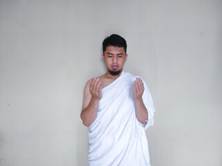 Muslim man praying while standing wearing ihram cloth