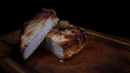 Roasted pork entrecote cut into pieces on a wooden cutting board. Grilled pork entrecote. Pork steak.