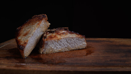 Roasted pork entrecote cut into pieces on a wooden cutting board. Grilled pork entrecote. Pork steak.