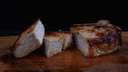 Roasted pork entrecote cut into pieces on a wooden cutting board. Grilled pork entrecote. Pork steak.