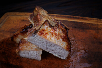 Roasted pork entrecote cut into pieces on a wooden cutting board. Grilled pork entrecote. Pork steak.