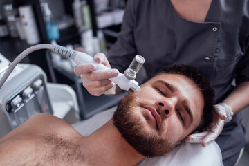 Caucasian man getting face peeling procedure in a beauty clinic, close up.