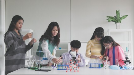 Group of schoolchildren studying science and doing microscopic analysis in the laboratory	