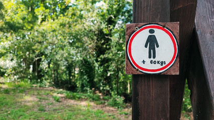 Restrictive sign with the image of a human symbol and a weight limit of 60 kg against the background of nature.