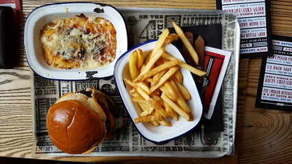 American style burger with skin on fries and mac and cheese side on a tray