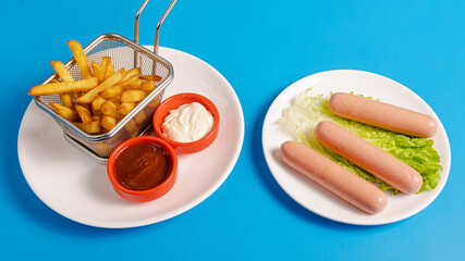 Fries basket and boiled sausages on plate
