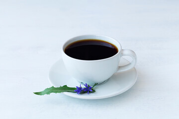 cup of coffee with flowers. delicious chicory drink in white Cup decorated chicory flowers on white background. hot and healthy drinks. coffee substitute. copy space.