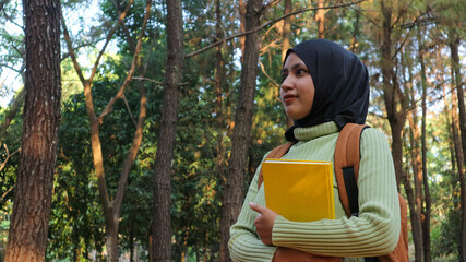 young muslim Woman holds book in her hands. Reading the book in the park during morning sun