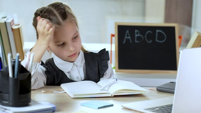 Disappointed girl slapping head with hand while sitting at desk with laptop