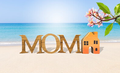 Mother's day card background idea, tropical style, mom wooden font and miniatrue wooden house model on tropical beach, outdoor day light