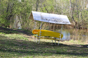 A lightweight portable gazebo stands on the riverbank in the park