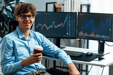 Profile of young stock trader with curly hair sitting against on dynamic financial exchange trading...