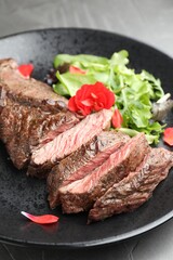 Pieces of delicious grilled beef meat and greens on table, closeup