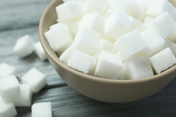 White sugar cubes in bowl on wooden table, closeup
