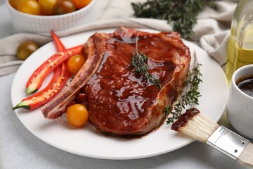 Raw marinated meat with thyme, chili pepper and basting brush on light table