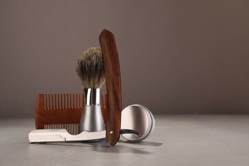 Moustache and beard styling tools on grey table. Space for text
