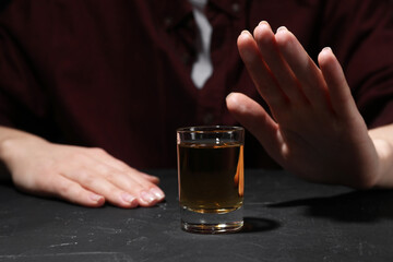 Alcohol addiction. Woman refusing glass of whiskey at dark textured table, closeup