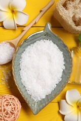 Flat lay composition with natural sea salt on yellow wooden table