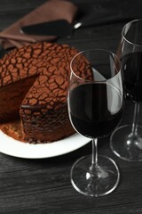 Delicious chocolate truffle cake and red wine on black wooden table