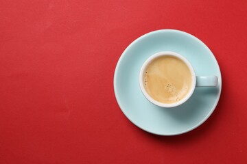 Aromatic coffee in cup on red background, top view. Space for text