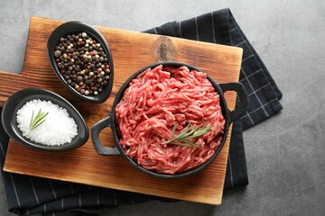 Raw ground meat in bowl and spices on grey table, top view