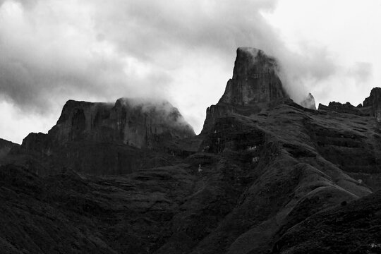 Ominous black and white view of mist surrounding the sentinel, the western buttress of the Amphitheater, in the Drakensberg mountains