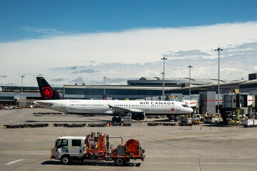 Fototapeta premium Mississauga, Canada, April 14, 2022; An Air Canada Airbus A321 jetliner parked at the jetway ramp to load passengers with the tails of other airplanes in the background