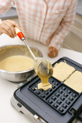 A young girl is cooking waffles.
