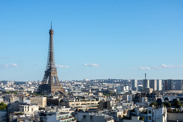 Fototapeta premium Panoramic view of the Eiffel tower, on the Parisian buildings in the center, Arc de Triomphe de l'Étoile, located on the Charles de Gaulle square, and at the western end of the Champs Elysées avenue 