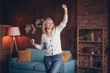 Photo portrait of lovely retired woman dance raise fists winning dressed casual outfit cozy home...