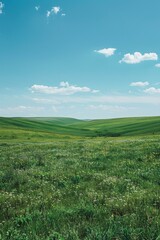 Obraz premium Scenic view of green rolling hills under blue sky with white clouds