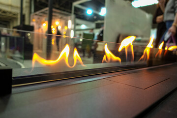 A bio-ethanol fireplace burns with orange flames in a dark room.