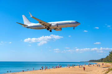 Airplane landing above beautiful beach with people on the beach and sea, travel