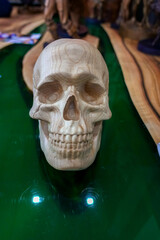 A white human skull made of wood lies on the table.