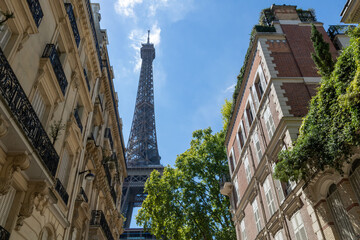 Eiffel tower, close up view from Rue de l'Université, surrounded by traditional French buildings,...
