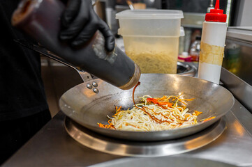 chef hand cooking Noodle with vegetables on restaurant kitchen