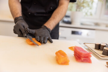 Chef, wearing gloves, preparing nigiri sushi