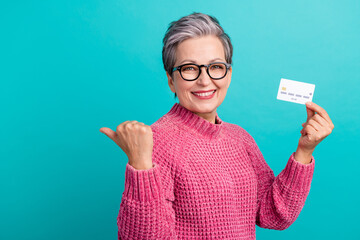 Portrait of optimistic woman wear pink pullover hold plastic card indicating at sale empty space...
