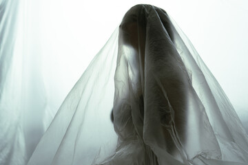 Silhouetted Figure Under Sheer Fabric Against Illuminated Backdrop
