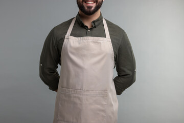 Smiling man in kitchen apron on grey background, closeup. Mockup for design