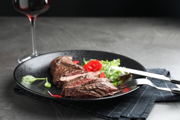 Delicious grilled beef meat served with greens on grey table
