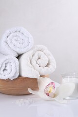 Spa composition with towels, orchid flower, candle and sea salt on white table