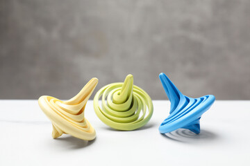 Bright spinning tops on white table, closeup