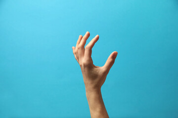 Woman holding something in hand on light blue background, closeup