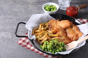 Tasty fish, chips, sauce and peas on grey table, closeup. Space for text