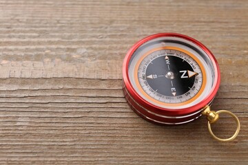 One compass on wooden table, closeup. Space for text